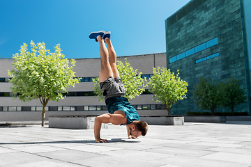 Image showing young man exercising and doing handstand outdoors