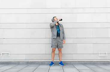 Image showing sportsman with bottle drinking water in city