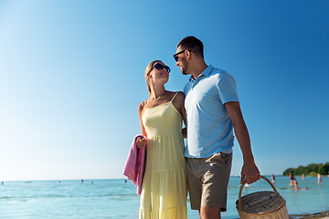 Image showing happy couple with picnic basket walking on beach