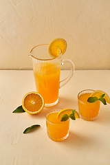 Image showing glasses with orange juice and peppermint on table