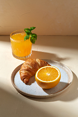 Image showing glass of orange juice and croissant on plate