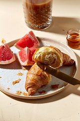 Image showing glass of coffee, croissant and grapefruit on table