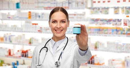 Image showing smiling female doctor holding jar of medicine