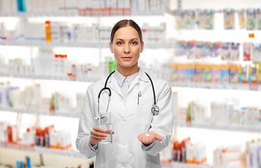 Image showing doctor with pills and glass of water at pharmacy