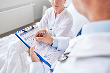 Image showing senior woman and doctor with clipboard at hospital