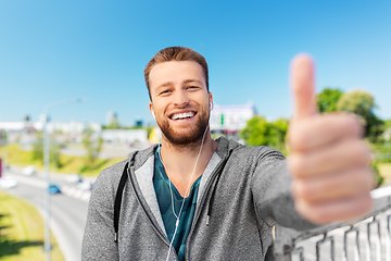 Image showing happy smiling man in earphone showing thumbs up