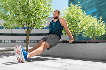 Image showing young man doing triceps dip on city street