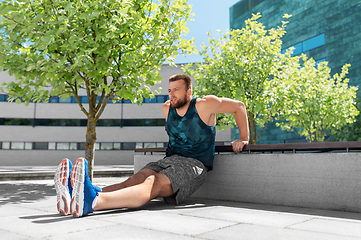 Image showing young man doing triceps dip on city street