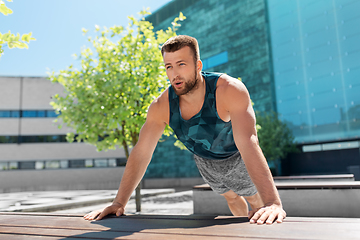 Image showing young man doing push ups on city street