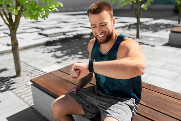 Image showing happy man with smart watch sitting on bench