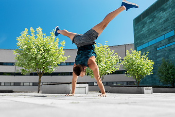 Image showing young man exercising and doing handstand outdoors