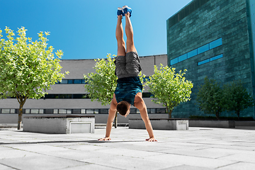 Image showing young man exercising and doing handstand outdoors