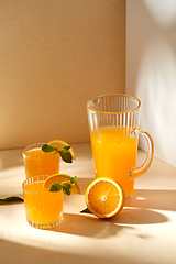 Image showing glasses with orange juice and peppermint on table