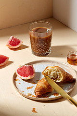 Image showing glass of coffee, croissant and grapefruit on table