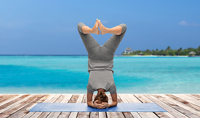 Image showing woman making yoga in headstand over ocean