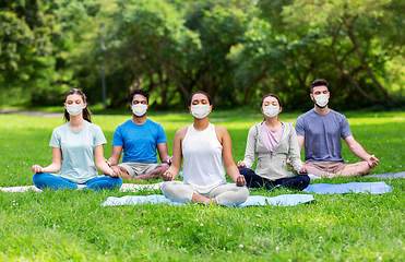 Image showing group of happy people in masks doing yoga at park