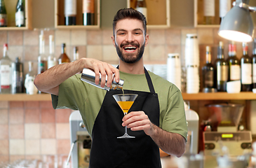 Image showing happy barman with shaker and glass preparing drink