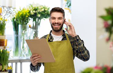 Image showing male gardener with clipboard calling on smartphone