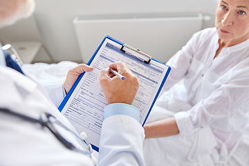 Image showing senior woman and doctor with clipboard at hospital