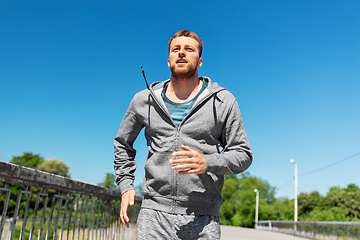 Image showing happy young man running across city bridge