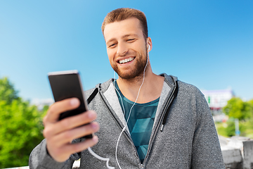 Image showing smiling young man with earphones and smartphone