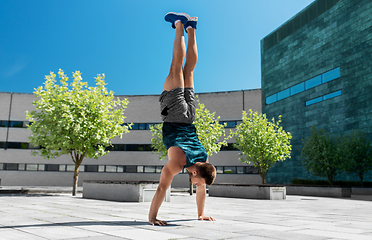 Image showing young man exercising and doing handstand outdoors