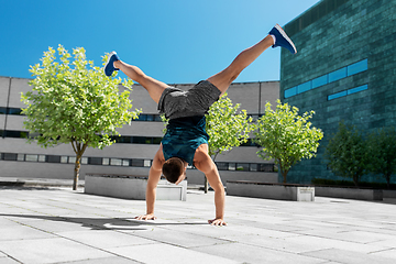 Image showing young man exercising and doing handstand outdoors