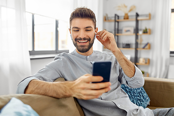 Image showing man in earphones listening to music on smartphone