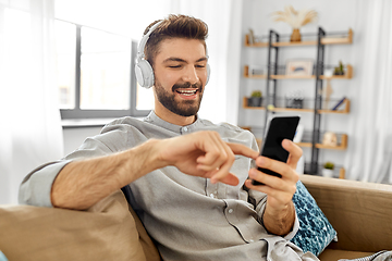 Image showing man in headphones listening to music on smartphone