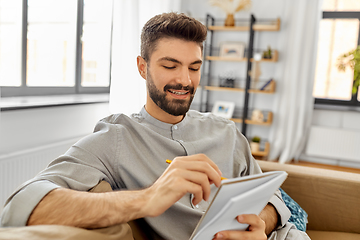 Image showing man writing to notebook drinking coffee at home