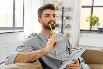 Image showing man writing to notebook and thinking at home