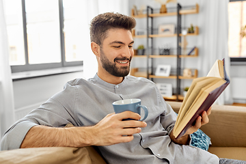 Image showing man reading book and drinking coffee at home