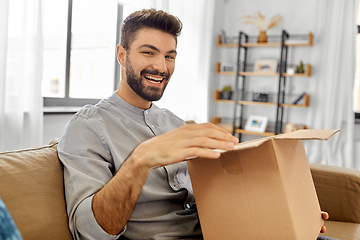 Image showing happy smiling man opening parcel box at home