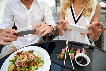 Image showing couple with smatphones photographing food