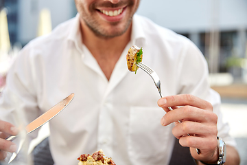 Image showing close up of happy man eating food at restaurant
