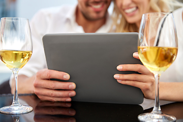 Image showing happy couple with tablet pc and wine at restaurant