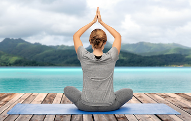 Image showing woman doing yoga in lotus pose over ocean