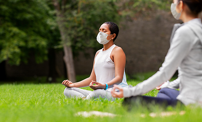 Image showing group of people in masks doing yoga at summer park