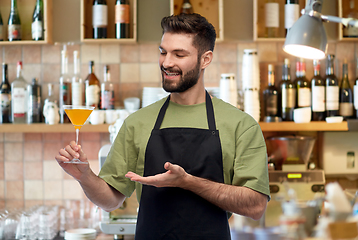 Image showing happy barman in apron with glass of cocktail