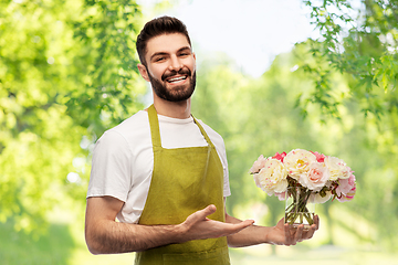 Image showing smiling male gardener with bunch of peony flowers