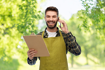 Image showing male gardener with clipboard calling on smartphone