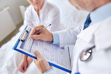 Image showing senior woman and doctor with clipboard at hospital