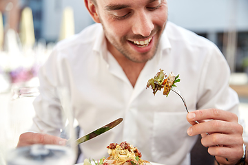 Image showing close up of happy man eating food at restaurant