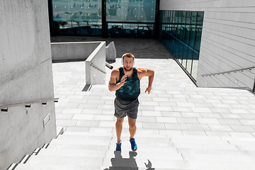 Image showing young man in headphones running upstairs outdoors