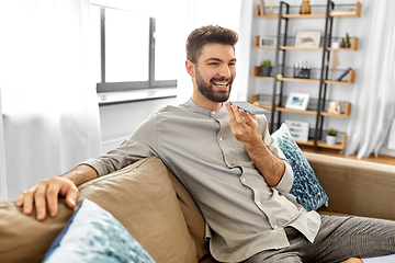 Image showing happy man with smartphone recording voice at home