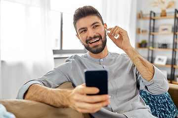 Image showing man in earphones listening to music on smartphone