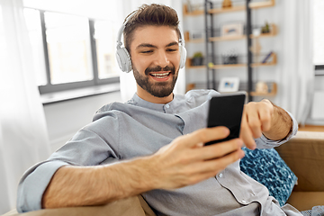 Image showing man in headphones listening to music on smartphone