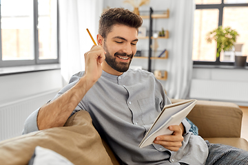 Image showing smiling man with to notebook and pencil at home