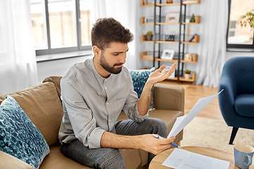 Image showing stressed man with bills at home