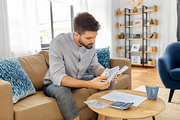 Image showing man with money and calculator filling papers